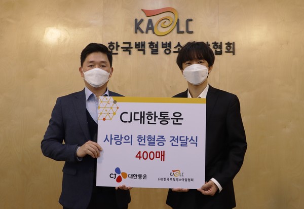 CJ대한통운 박진규 부장(왼쪽)이 한국백혈병소아암협회 서용화 과장(오른쪽)에게 헌혈증을 전달하고 기념촬영 하고 있다.