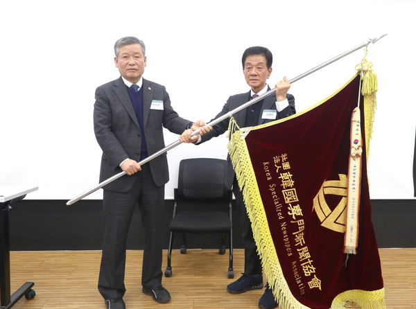 박두환 전임회장(왼쪽)이 김광탁 신임회장에게 협회기를 전달하고 있다.