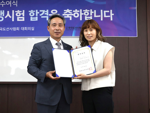 도선사협회 조용화 회장(왼쪽)이 한국 최초 여성도선수습생 구슬씨에게 합격증을 전달하고 기념 촬영하고 있다.
